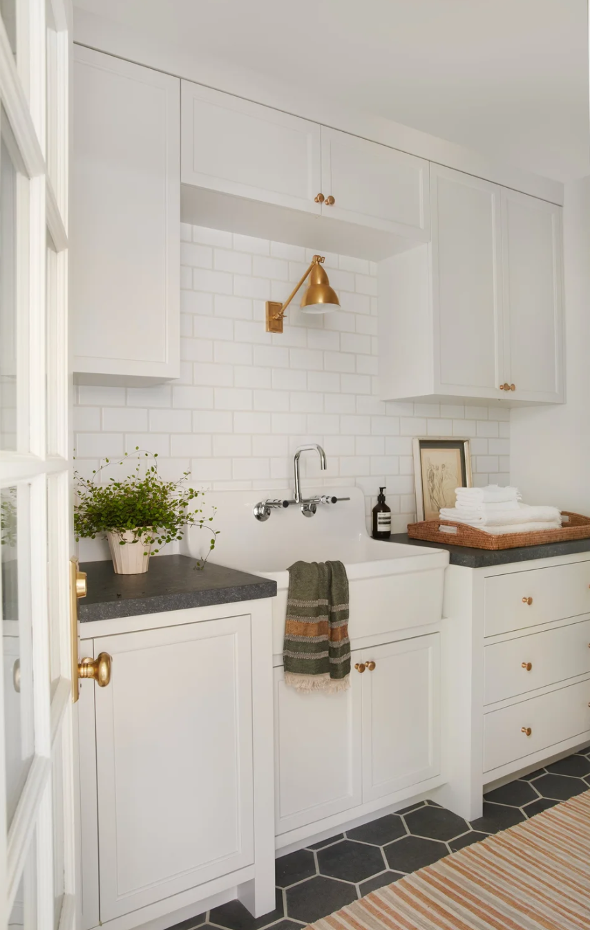 White laundry room with farmhouse sink, subway tile, brass sconce, and hexagonal slate floor, Hidden Hills, California, by Tammy Randall Wood / Interior Archaeology